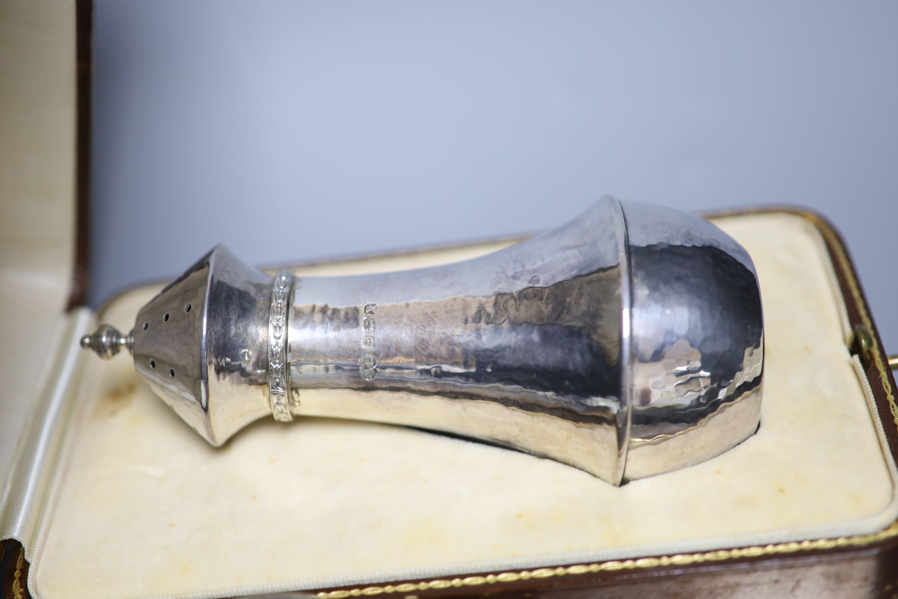 A George V Arts & Crafts silver baluster sugar caster, by Albert Edward Jones, 14.8cm, cased, a five-piece engine-turned dressing table set and two cased Christening sets